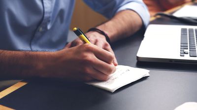 A man's hands writing notes